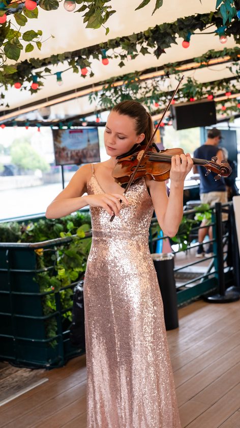 Violoniste en robe à sequins jouant sur le pont du bateau